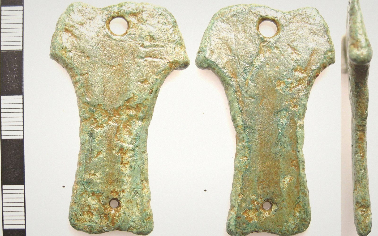 Corroded bronze sword handle fragment shown from front, back and side views beside a scale