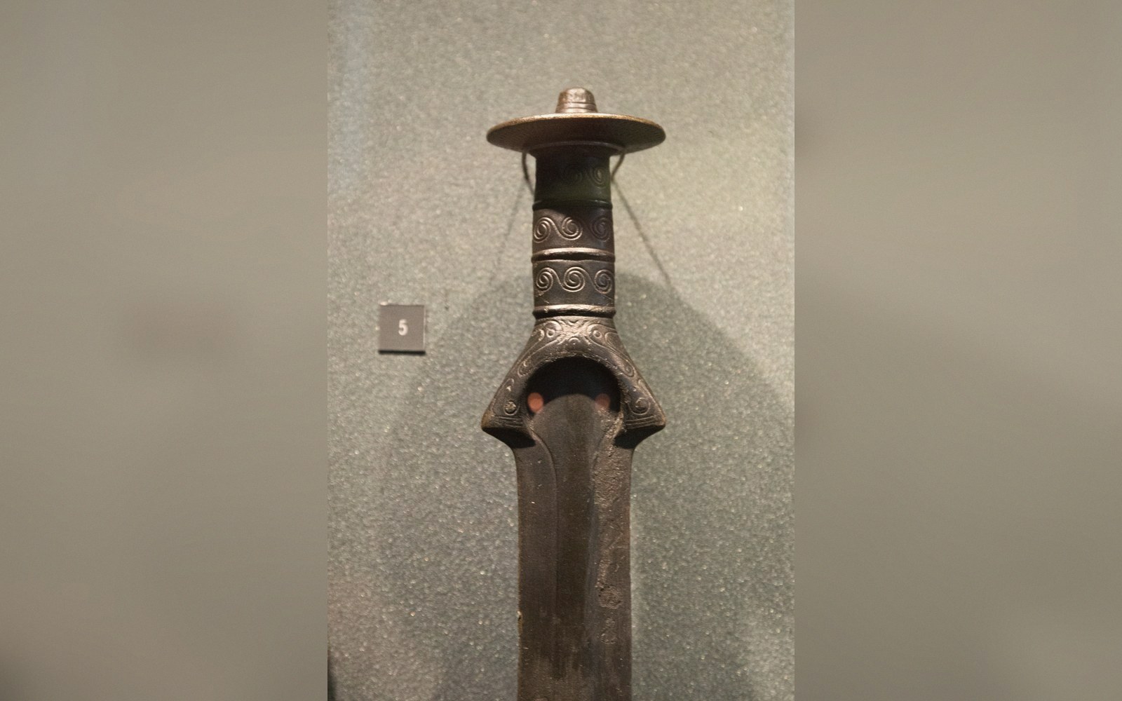 A bronze sword laid on a plain conservation bench